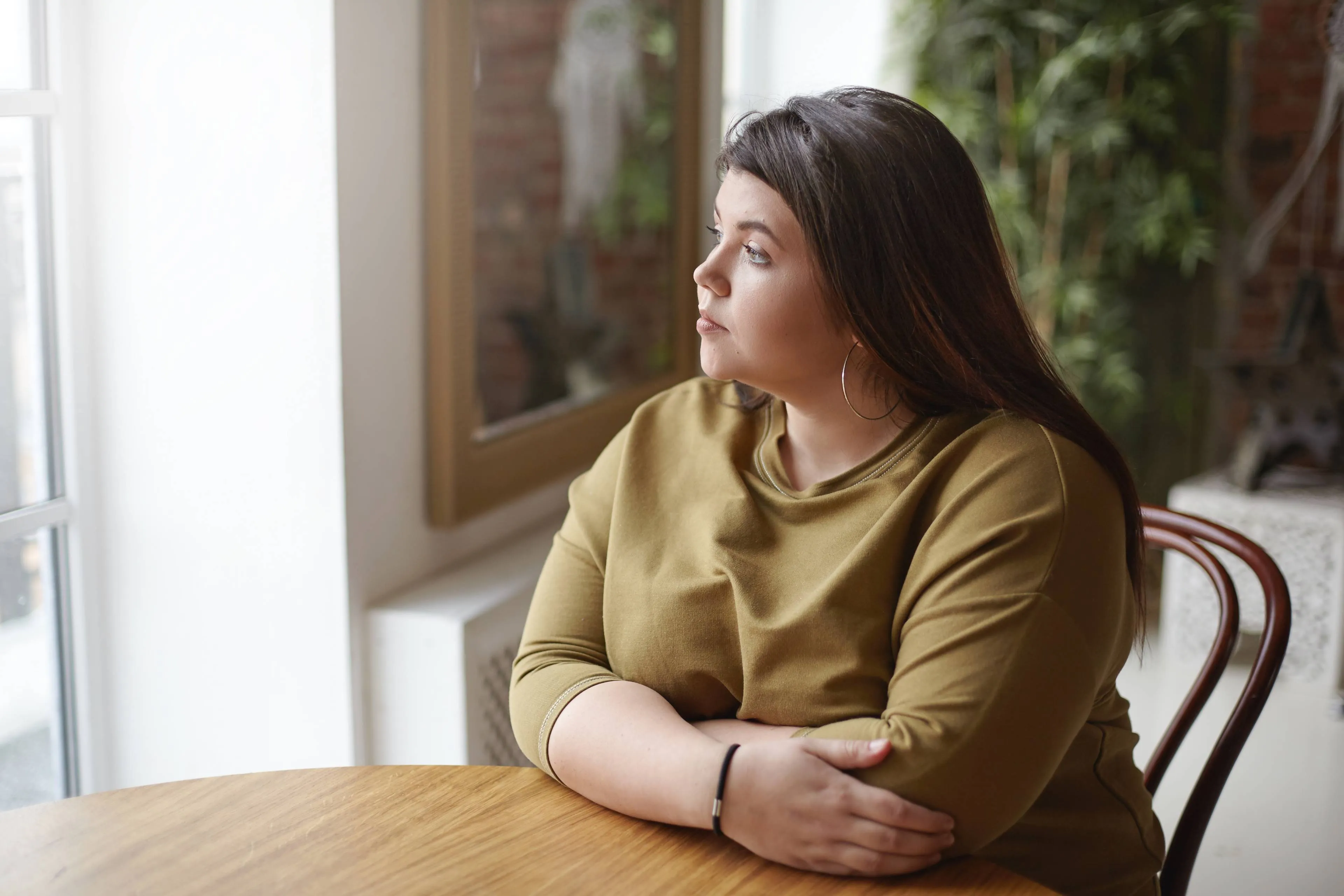loneliness concept young brunette plus size woman with black hair sitting cafe table feeling lonely spending time alone waiting her lunch looking through window with sad pensive expression1
