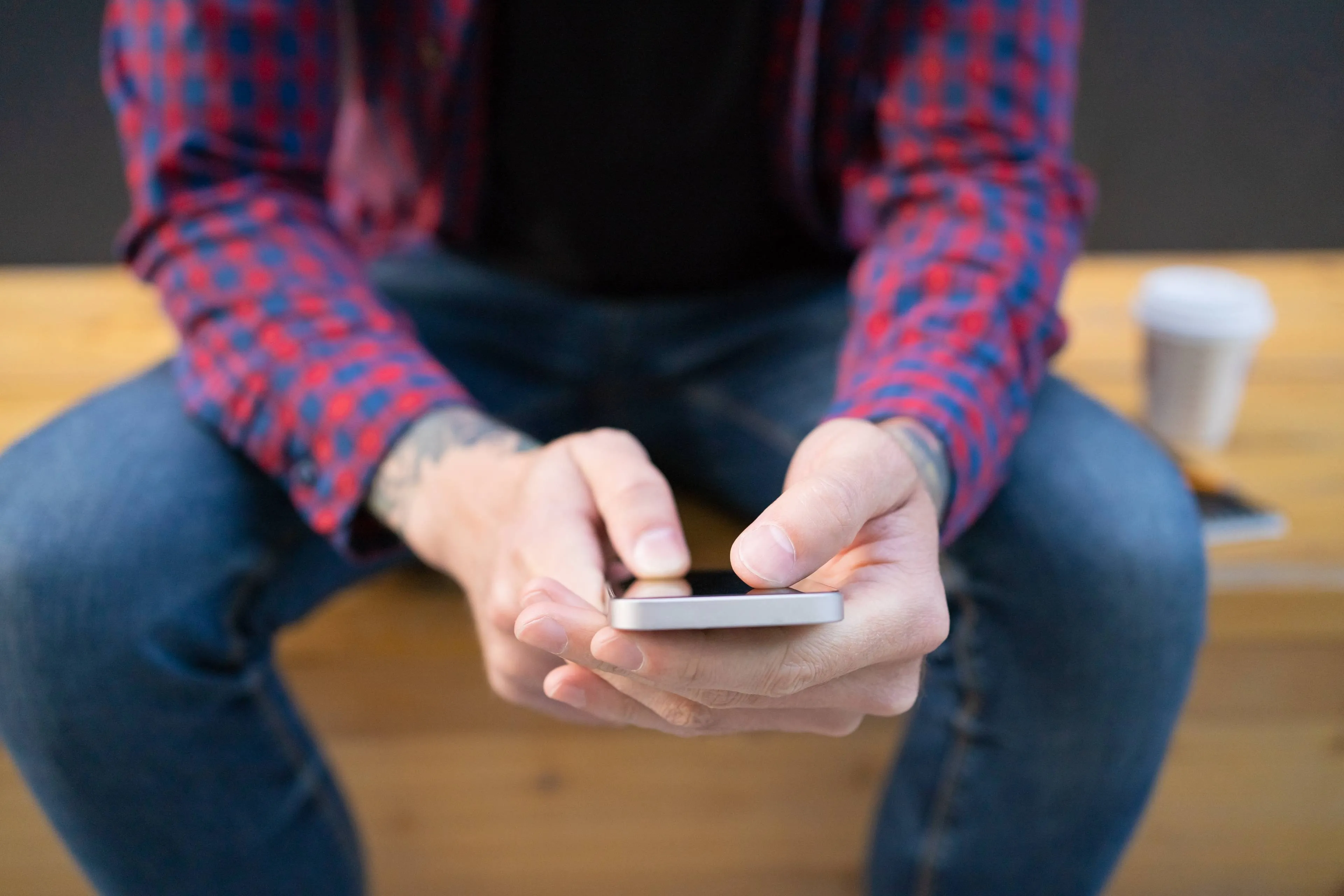 unrecognizable man sitting wooden bench with phone
