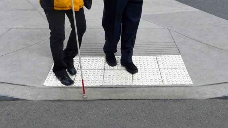 blinde met stok en begeleiding