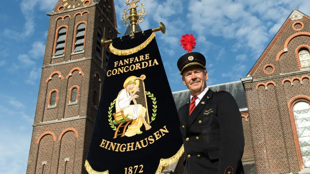 fanfare concordia einighausen vaandeldrager met vaandel bij de kerk
