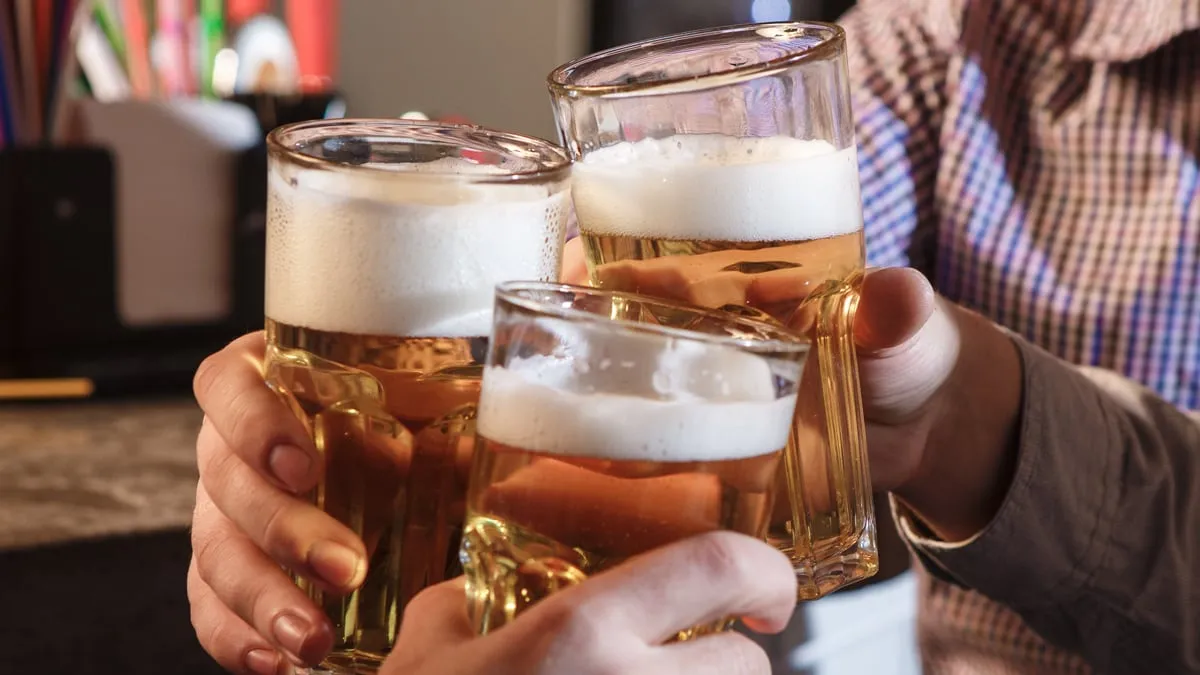 gelukkige vrienden die bier drinken bij teller in bar