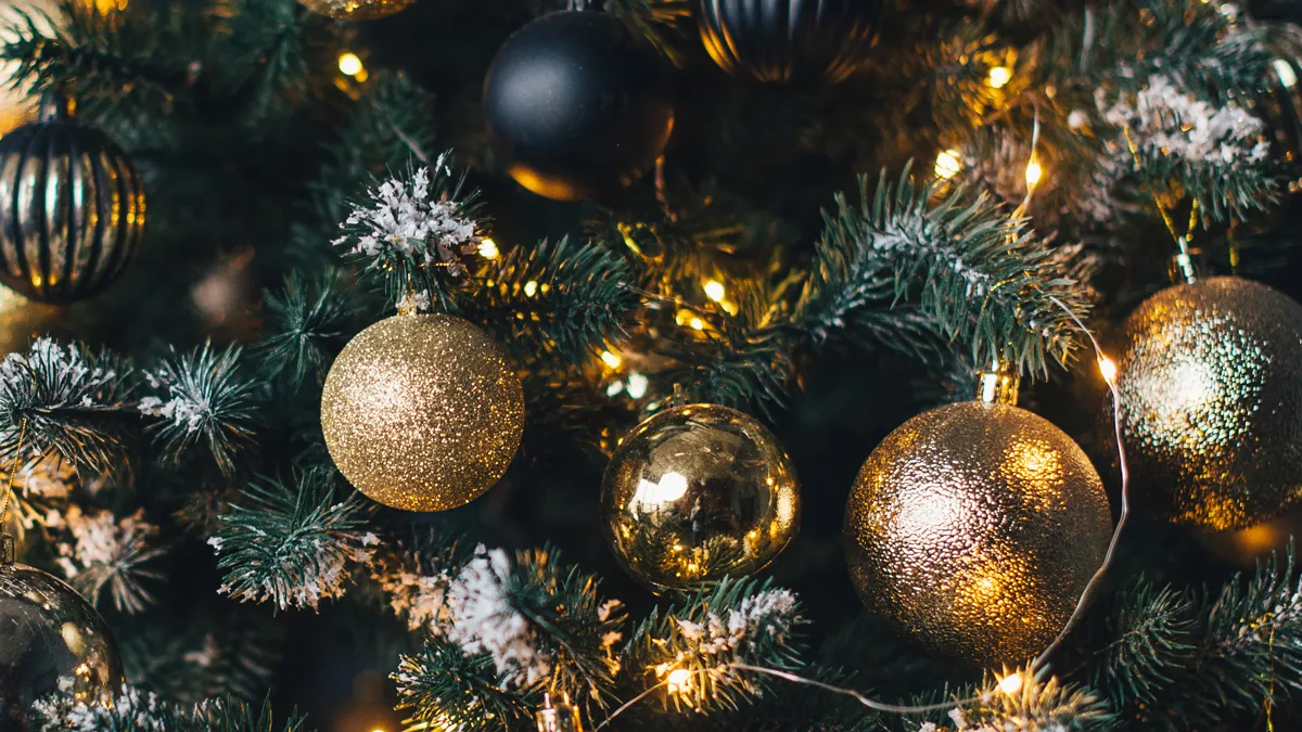 kerstboom versierd met slingers en gouden ballen op een donkere muur