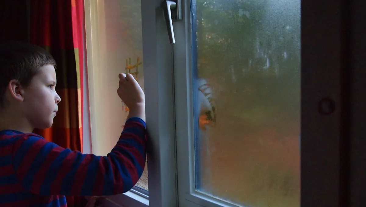 kind tekent op beslagen raam