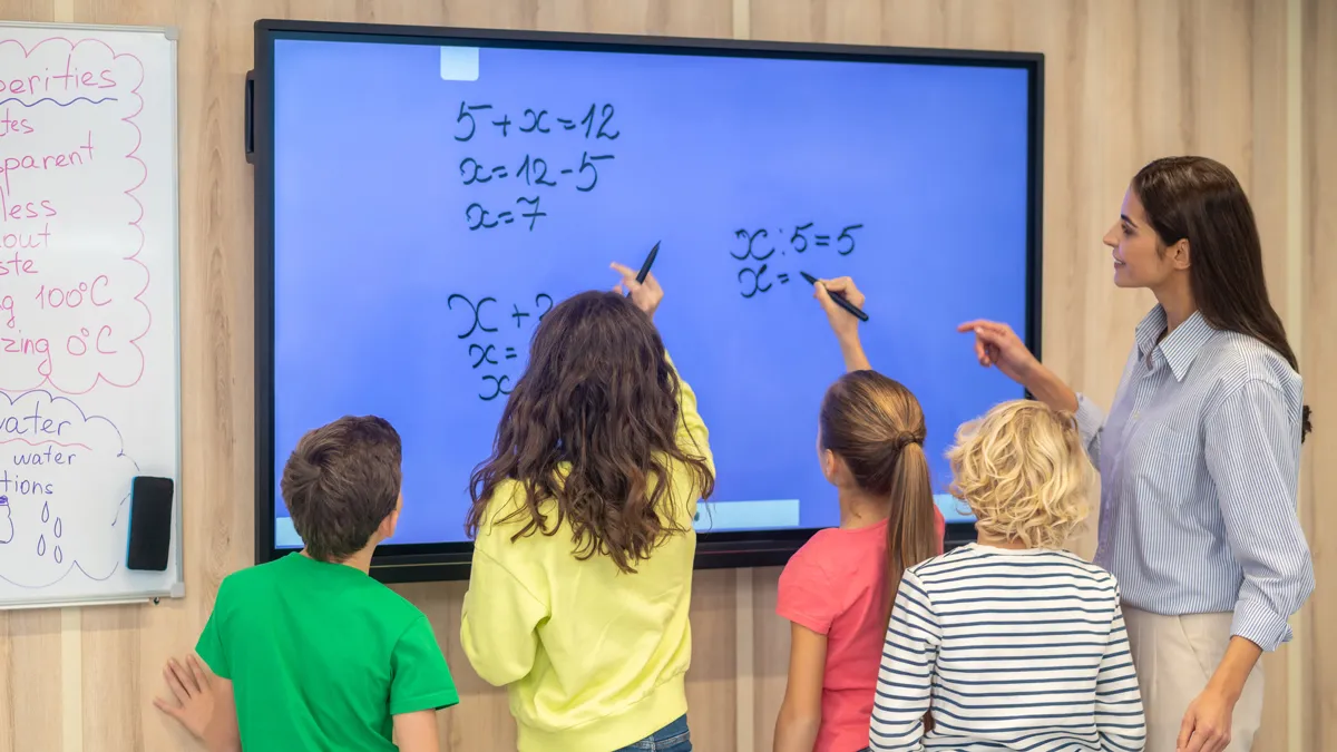 kinderen schrijven op smartboard lerares