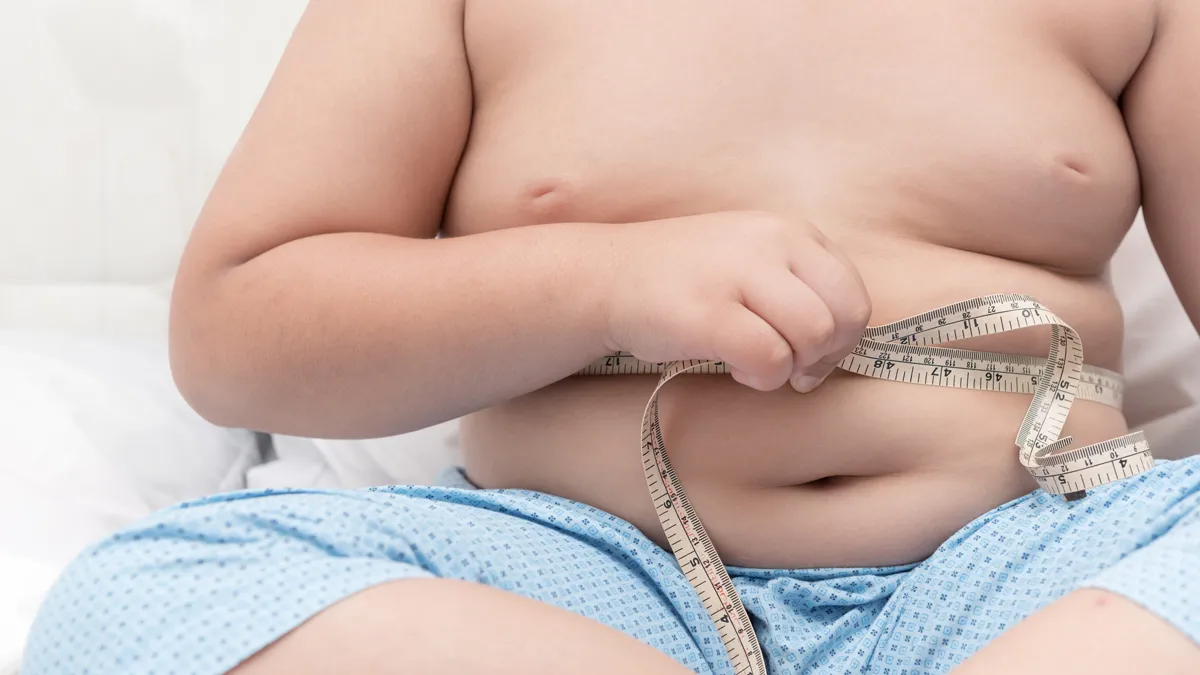 obesitas dikke jongen zijn buik meten met meting tape