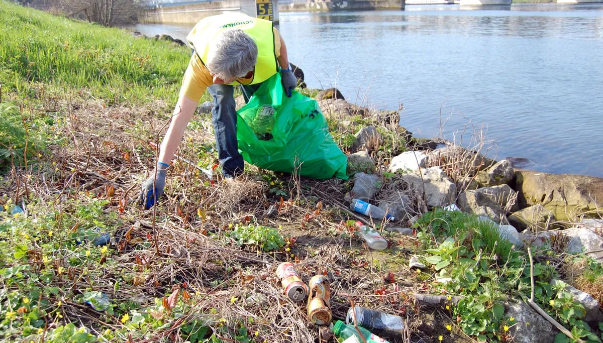 vrijwilliger ruimt afval op aan maasoever