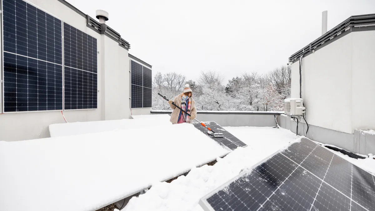 vrouw maakt zonnepanelen schoon van sneeuw