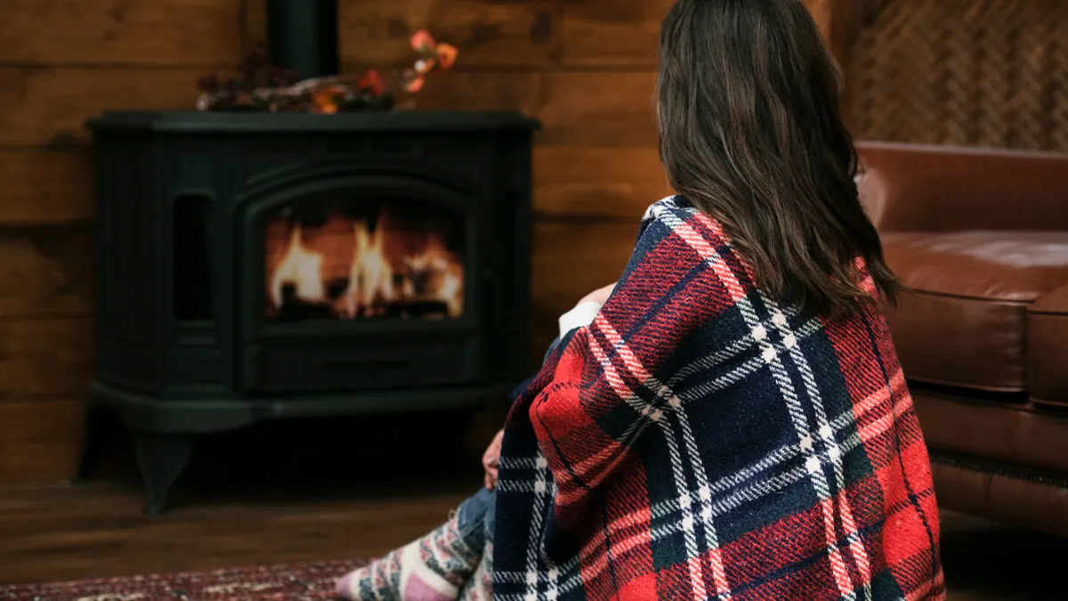 vrouw met deken naast brandende houtkachel
