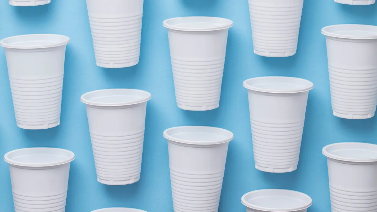 witte plastic bekers voor eenmalig gebruik op een blauwe achtergrond