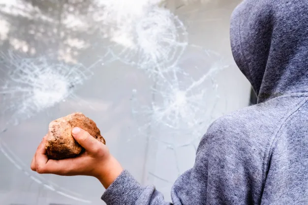 kind houdt een steen om het tegen een glas te gooien en een raam te breken 47726 7801