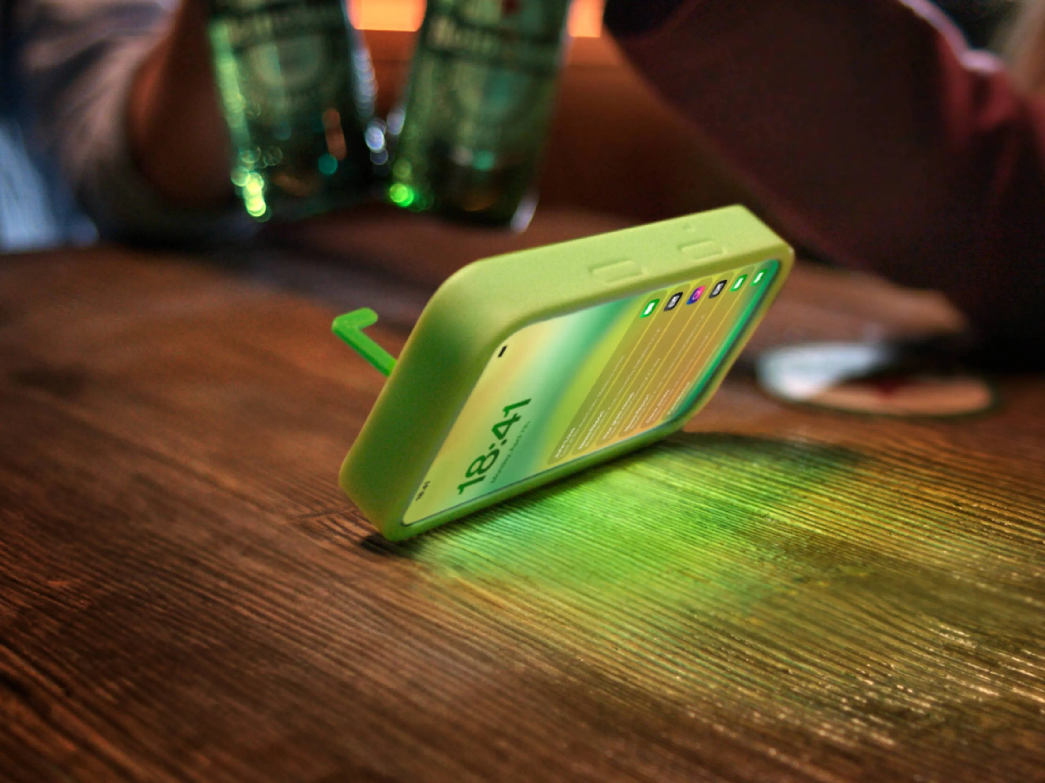 Heineken The Flipper smartphonehoesje op een tafel terwijl hij net omdraait. Op de achtergrond twee flesjes Heineken
