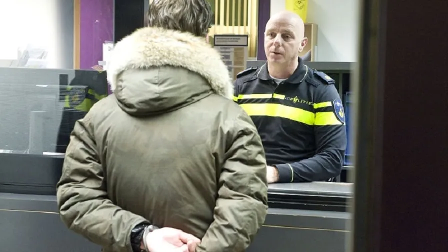 arrestant voor de balie in gesprek met agent
