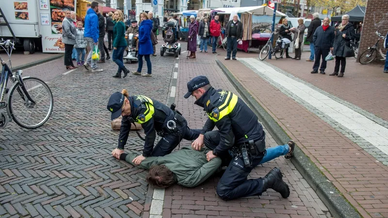 twee agenten drukken verdachte tegen de grond