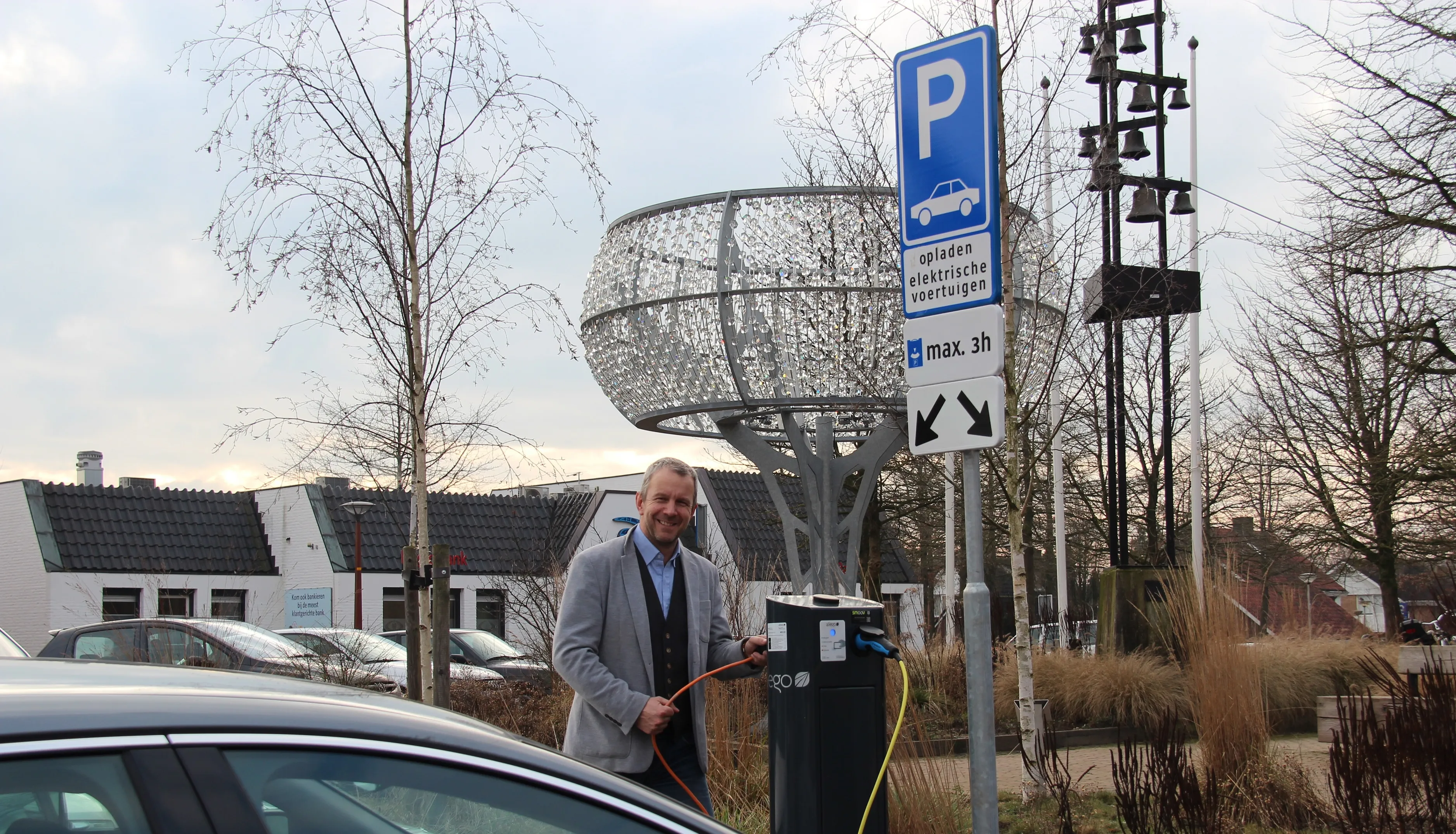 wethouder vleerbos naast laadpaal voor gemeentehuis