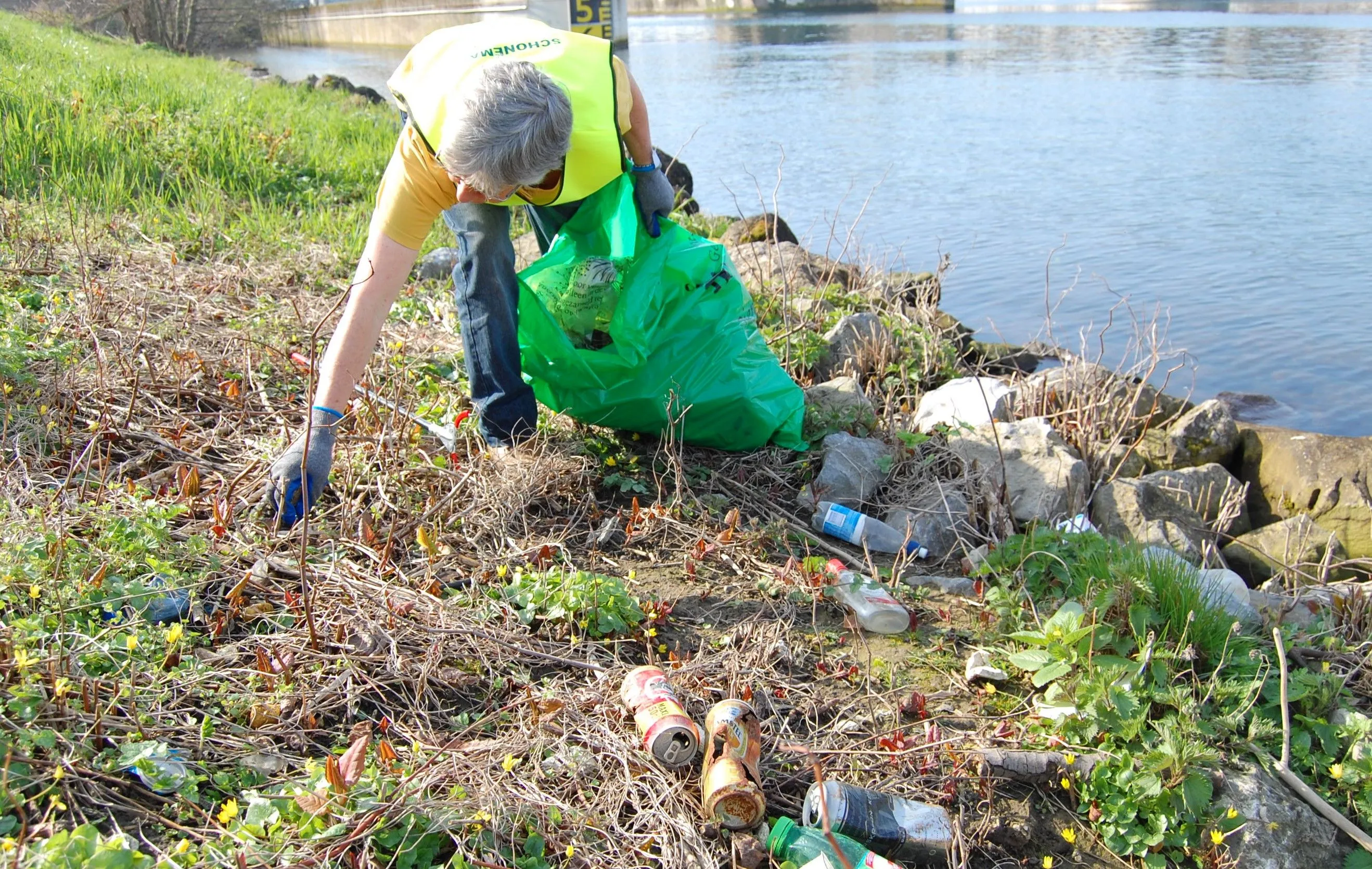 vrijwilliger ruimt afval op aan maasoever