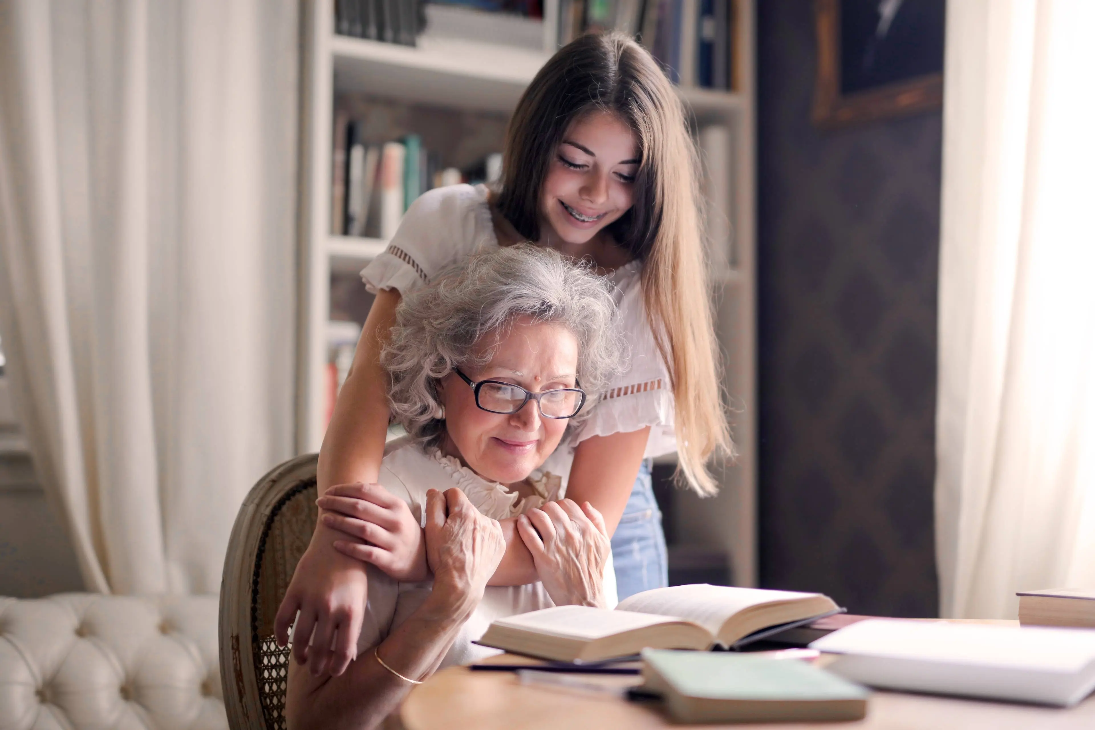 oma_bejaarde_kleindkind_meisje_knuffel_tafel_boeken_lezen