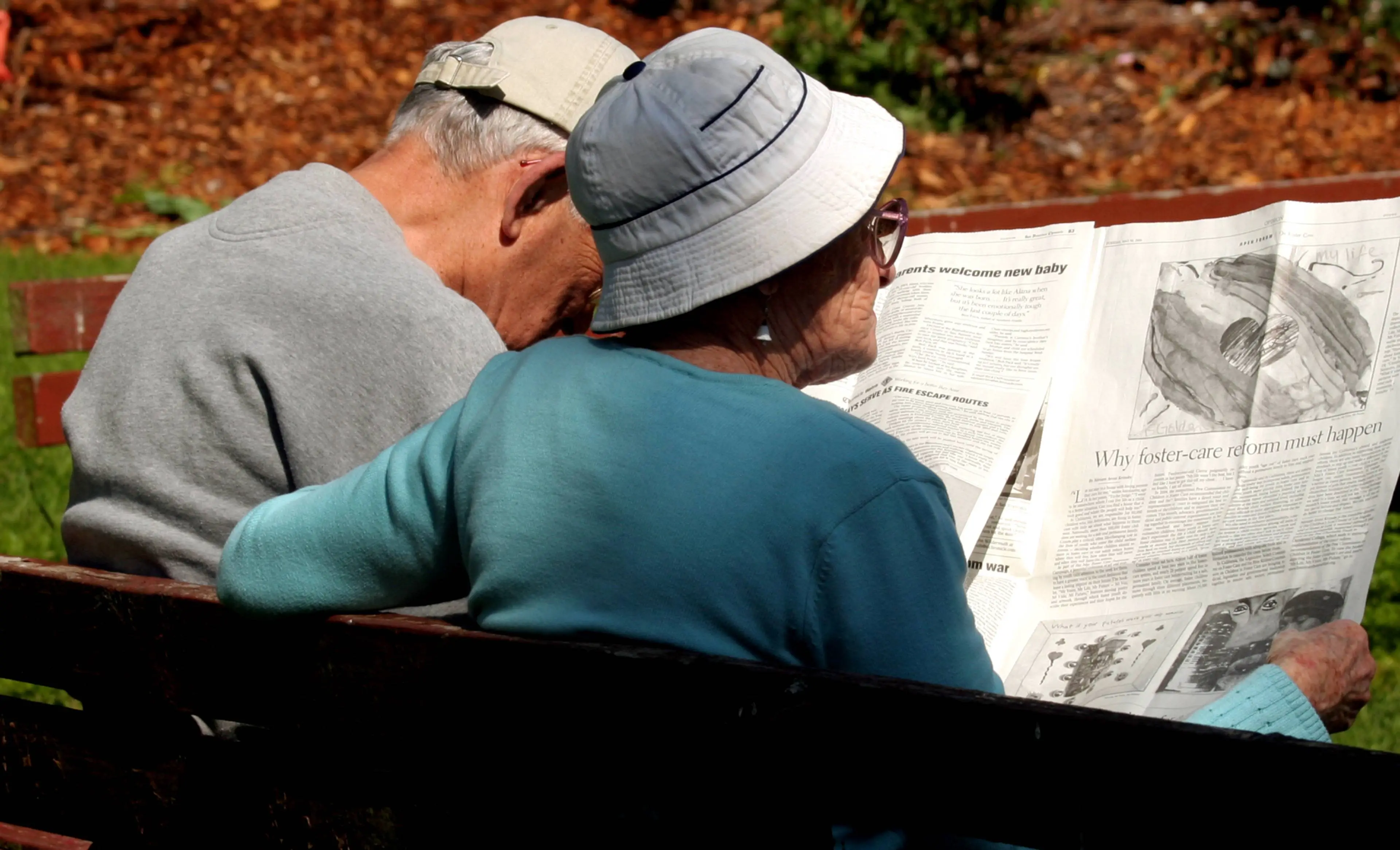 Stel leest krant op bankje 2