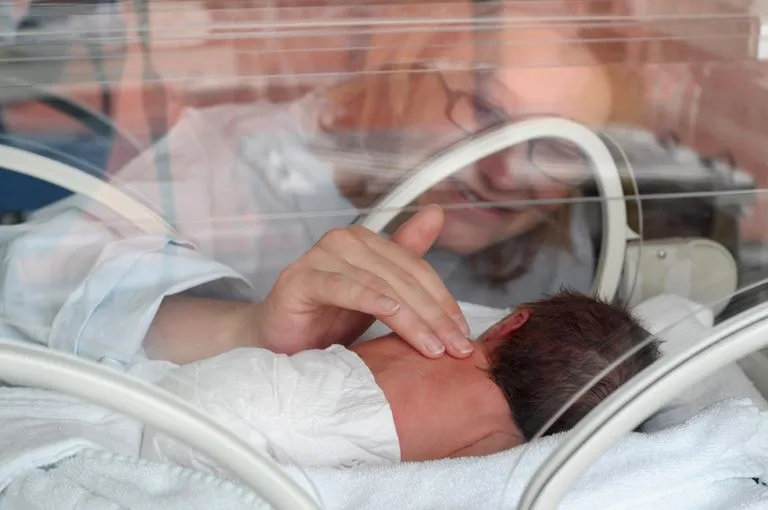 baby in couveuse en moeder zit erbij