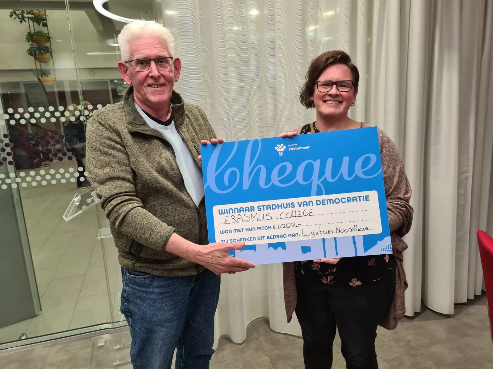 vrijwilliger rob en sociaal cultureel werker odettte nemen de cheque in ontvangst foto stichting piezo