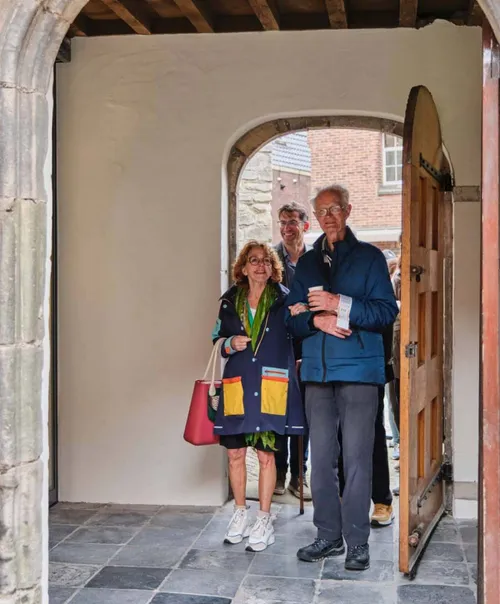 Wethouder Cultuur en Erfgoed, Anjo van de Ven maakt gebruik van de nieuwe ingang aan de Langestraat. Meneer Miedema loopt met haar mee.&nbsp;