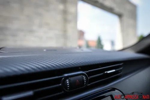 Foto del dettaglio della plancia di una Alfa Romeo Giulietta Veloce, con focus specifico sulla plastica con effetto carbon look.