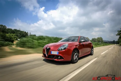 Foto di una Alfa Romeo Giulietta Veloce dinamica, con ripresa del tre quarti anteriore su una strada di campagna rettilinea
