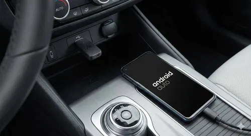 Adattatore wireless per Android Auto inserito nella porta USB dell'auto con uno smartphone connesso nelle vicinanze