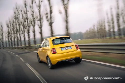 Foto dinamica posteriore della FIAT 500 Hybrid gialla su strada asfaltata