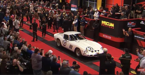 nell'immagine si vede la Ferrari GTO 250 bianca al centro di una casa d'aste e tutte intorno persone che fanno foto e che cercano di acquistare il veicolo