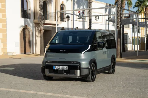 La vista frontale della Kia PV5 Passenger, bicolore e in una piazza soleggiata