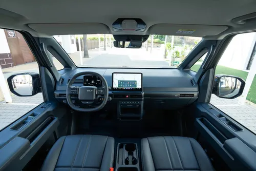 Gli interni della Kia PV5 con sedili neri, display dell'infotainment da 12,8 pollici e quadro strumenti digitale