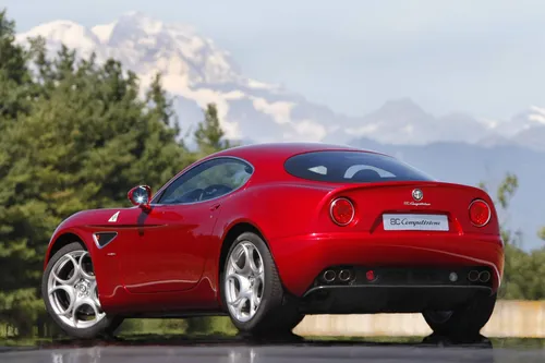 L'Alfa Romeo 8C Competizione, verniciata nel classico Rosso Alfa, fotografata di tre quarti posteriore in pista e con le Alpi sullo sfondo