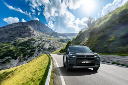 Nuova Suzuki Across plug-in hybrid in ripresa dinamica anteriore su una strada con montagne dietro