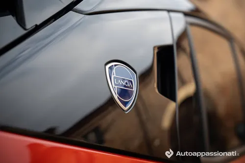 Lancia Ypsilon HF Line ibrida di colore arancione logo Lancia sul montante C in contrasto di colore nero