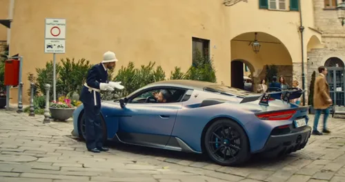 Maserati GT2 Stradale blu metallizzato ferma nel centro storico di Sanremo mentre il guidatore parla con un vigile urbano, scena tratta dallo spot TV della Fiat Topolino