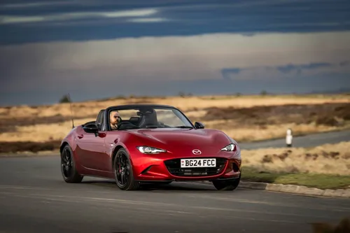Un esemplare di Mazda MX-5 guidato su una strada inglese piena di curve e verniciata nel rosso Mazda, il Soul Red Crystal