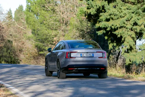La nuova Volvo ES90 ripresa da dietro mentre percorre una strada tra gli alberi
