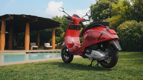 vespa sprint s di colore rosso ripresa dal posteriore davanti a una piscina