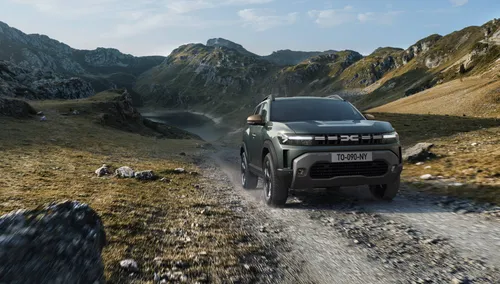 Dacia Duster percorre uno sterrato con sfondo campagne e montagne
