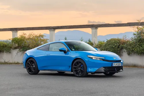 La nuova Honda Prelude Hybrid 2026 verniciata in blu fotografata di tre quarti anteriore con un tramonto e un ponte alle sue spalle