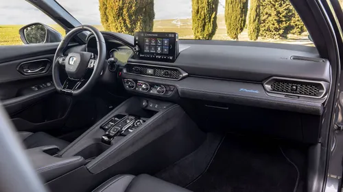 Gli interni della Honda Prelude Hybrid 2026, con rivestimenti neri e dettagli blu, fotogrfata in una giornata di sole con dietro degli alberi