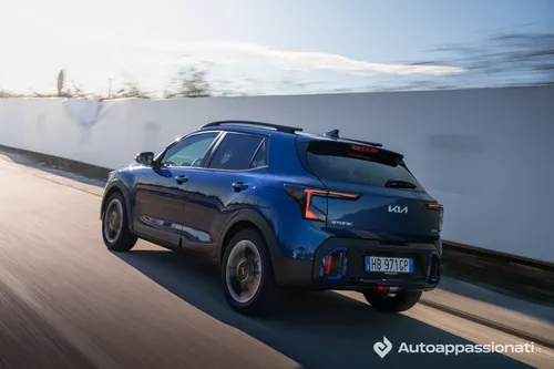 La Kia Stonic blu metallizzata ripresa dal posteriore mentre percorre una strada pubblica