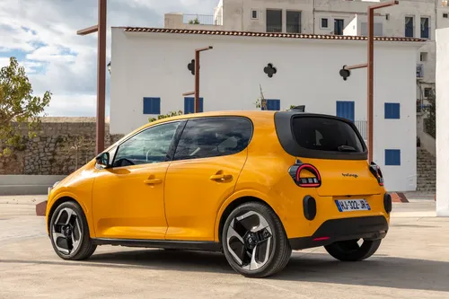 Una foto del posteriore di tre quarti della Renault Twingo 2026 IV E-Tech verniciata in Giallo Mango scattata in una piazza di una cittadina di mare