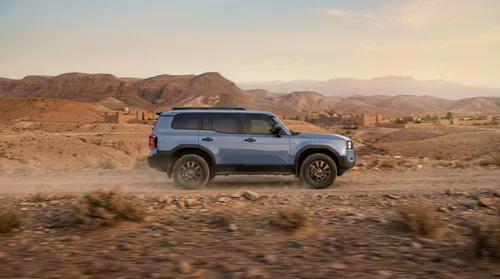 Toyota Land Cruiser di lato di colore blu con sfondo deserto