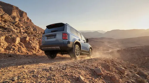 Toyota Land Cruiser di lato di colore blu posteriore che procede su una strada sterrata