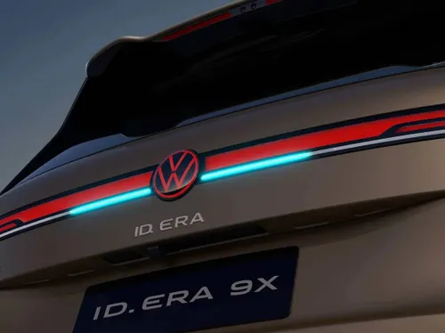 Dettaglio posteriore del SUV Volkswagen ID. Era 9X color bronzo. Spicca la firma luminosa a tutta larghezza con barra LED bicolore rossa e azzurra, divisa al centro dal logo VW illuminato di rosso. Sotto, il lettering ID. ERA