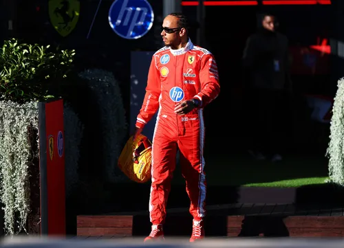 lewis hamilton pilota ferrari che cammina con la tuta rossa e il casco lego giallo