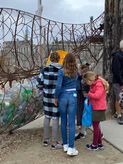 leerlingen van het kompam uit ijmuiden gooien plastic flessen in kunstwerk catchfish
