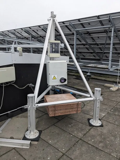 Close-up van de optische antenne op het dak van Flux, gemonteerd op zijn steunframe. De eigenlijke antenne is de grijze doos. Daaruit steekt de apertuur waardoor het infrarode licht wordt verzonden en ontvangen.