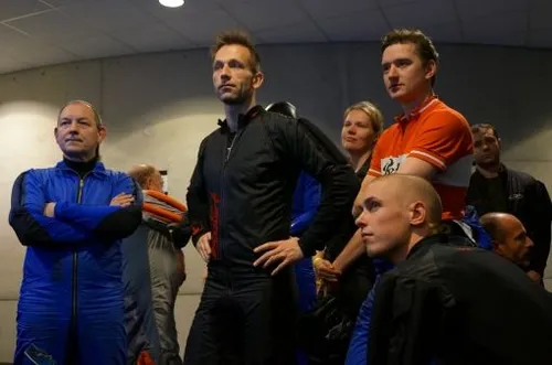 Overal hangen schermen waar de deelnemers kunnen zien wat de andere teams doen.